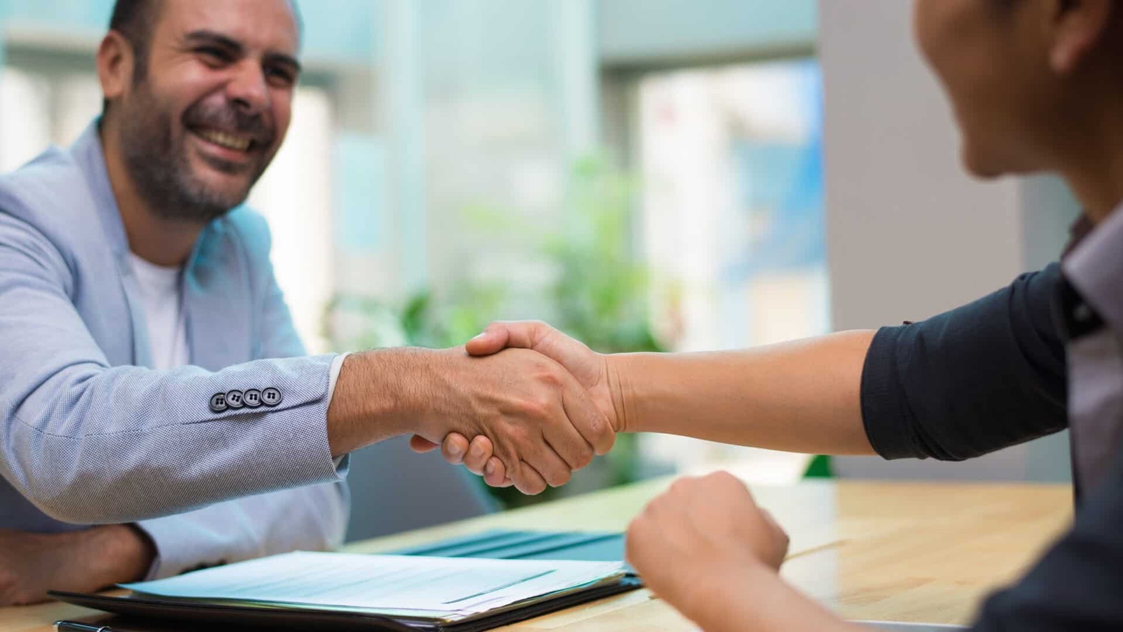 Insurance broker greeting a client over a policy in a bright office